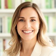 Porträt von Mag. Sabine Hofbauer mit freundlichem Lächeln vor einer hellen Bücherwand